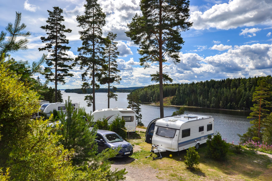 Husvagnar på en skogsnära campingplats med utsikt över en sjö i Värmland.