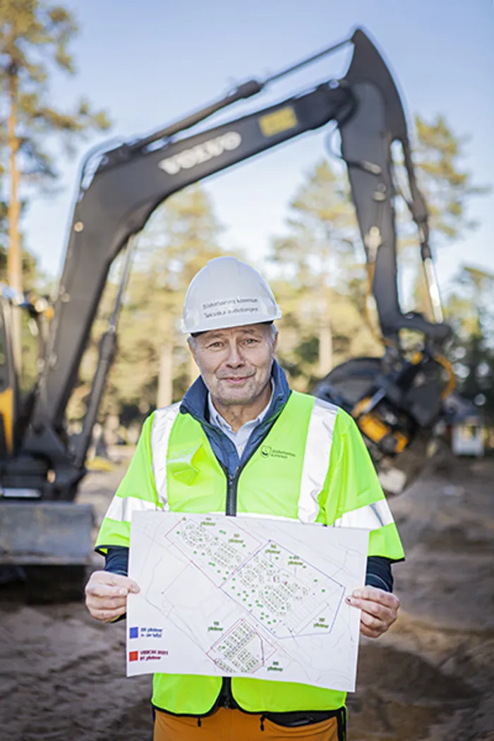 Thomas Gunnarsson i arbetskläder och skyddshjälm med karta i handen.