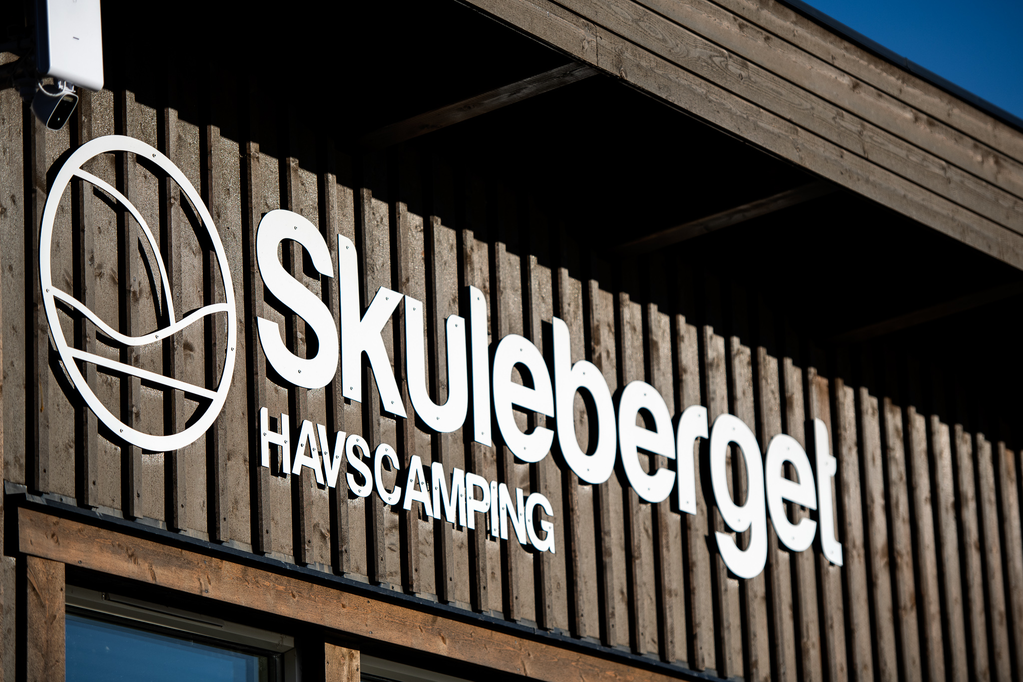 Skylt för Skulebergets Havscamping monterad på en trävägg